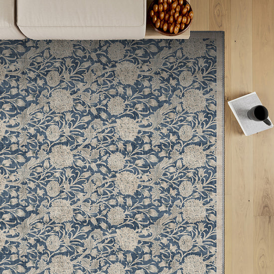 Floral patterned rug on a wooden floor with a sofa and decorative items.