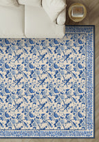 Blue and white floral and bird patterned rug on a wooden floor.
